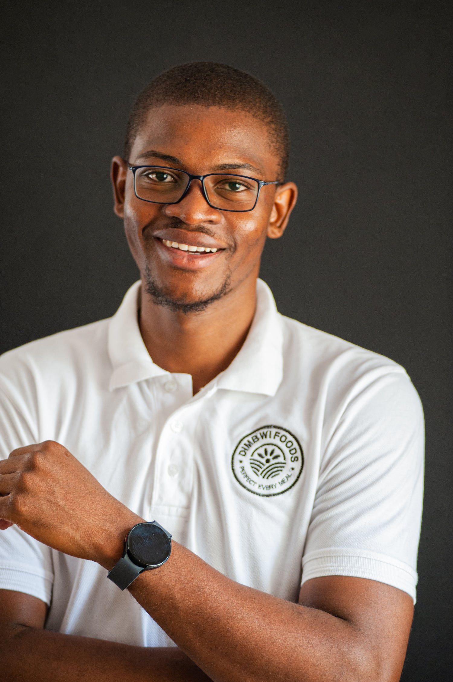 Portrait of Tionge Mkandawire Co-Founder of Dimbwi Foods in a white golf t-shirt with the Dimbwi Foods Logo in black